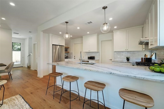 kitchen with kitchen peninsula, backsplash, white cabinetry, and light stone counters