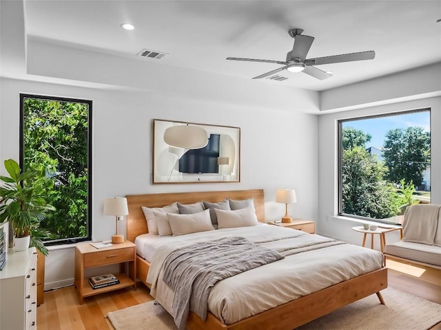 bedroom with ceiling fan, light hardwood / wood-style floors, and multiple windows