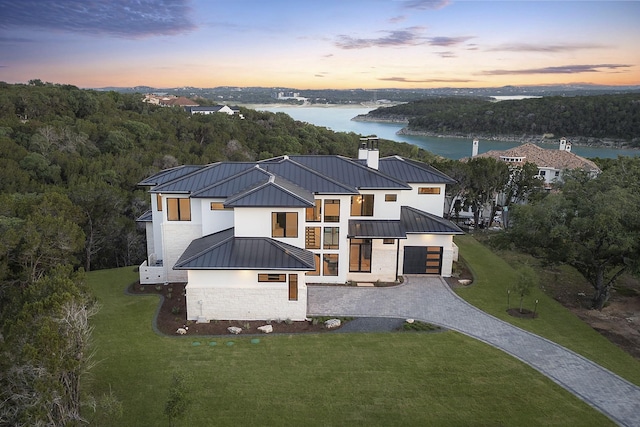 aerial view at dusk featuring a water view