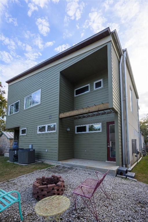 back of house with an outdoor fire pit and central AC