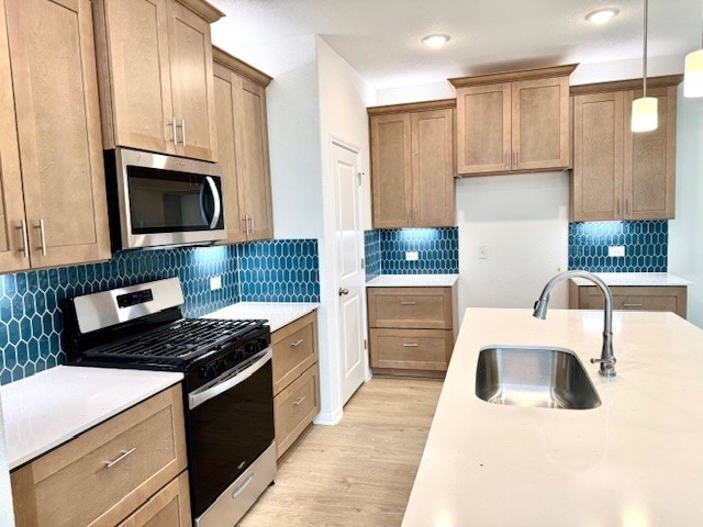 kitchen with light wood-type flooring, backsplash, stainless steel appliances, sink, and pendant lighting