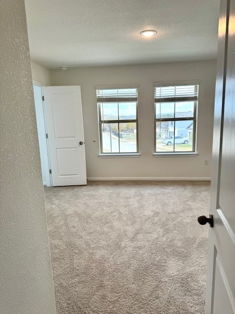 spare room with light carpet and a textured ceiling