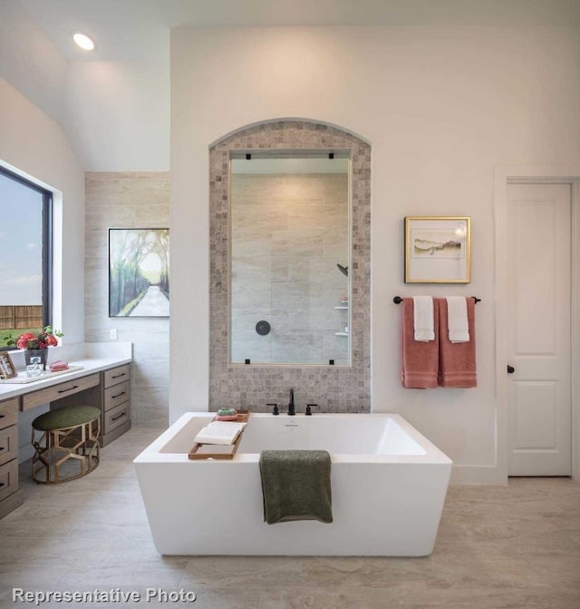 bathroom with vanity, tile walls, independent shower and bath, and vaulted ceiling