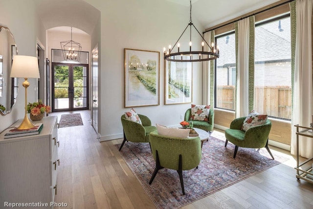 living area with hardwood / wood-style flooring, a notable chandelier, and french doors