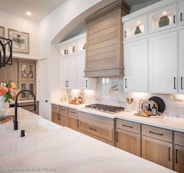 kitchen with white cabinetry, sink, and premium range hood