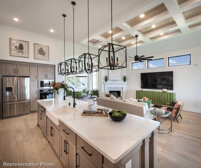 kitchen with appliances with stainless steel finishes, coffered ceiling, beam ceiling, light hardwood / wood-style flooring, and a large island