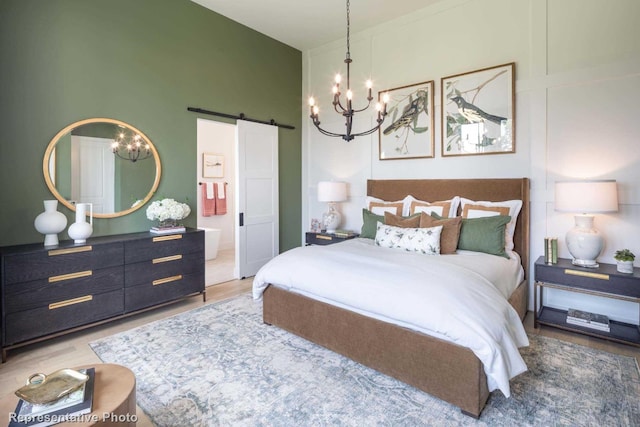 bedroom with a barn door, a notable chandelier, and hardwood / wood-style flooring