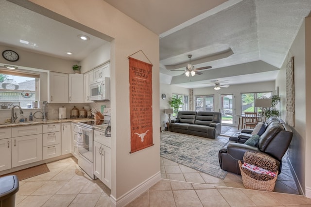 kitchen featuring a wealth of natural light, sink, white cabinets, and white appliances