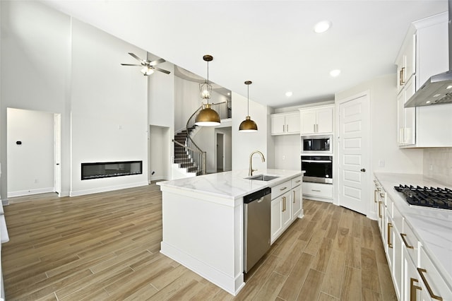 149 Golden Sage Ave, Georgetown, TX 78633 - kitchen with appliances with stainless steel finishes, wall chimney exhaust hood, light wood-type flooring, a glass covered fireplace, and recessed lighting