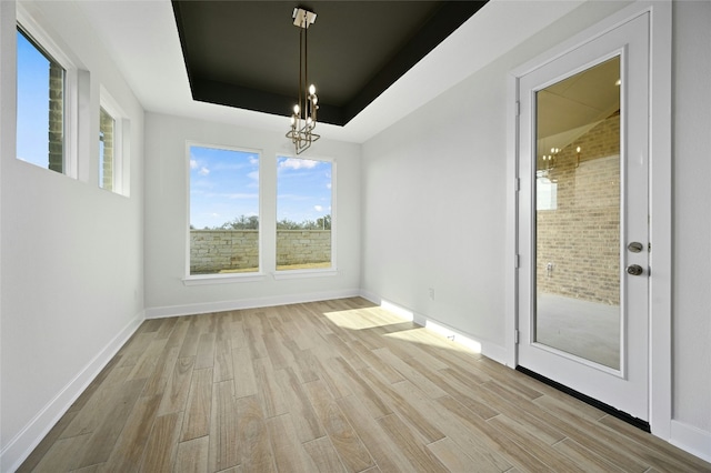 149 Golden Sage Ave, Georgetown, TX 78633 - unfurnished dining area featuring wood finished floors, a chandelier, and a tray ceiling
