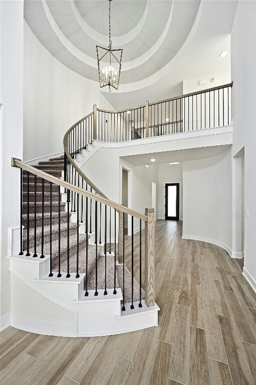 149 Golden Sage Ave, Georgetown, TX 78633 - staircase with wood finished floors, a chandelier, a towering ceiling, and a tray ceiling