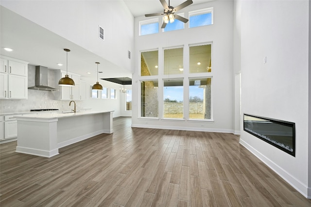 149 Golden Sage Ave, Georgetown, TX 78633 - unfurnished living room with a ceiling fan, wood finished floors, healthy amount of natural light, a glass covered fireplace, and a towering ceiling