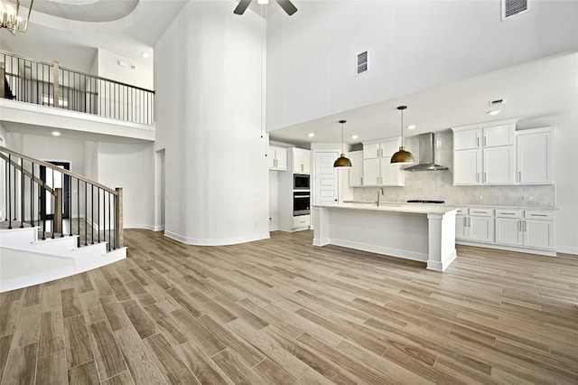 149 Golden Sage Ave, Georgetown, TX 78633 - unfurnished living room featuring a high ceiling, light wood-style flooring, stairs, ceiling fan, and recessed lighting