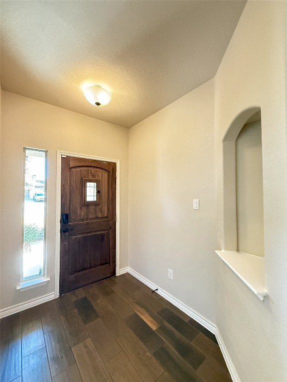 foyer with a textured ceiling and dark hardwood / wood-style floors