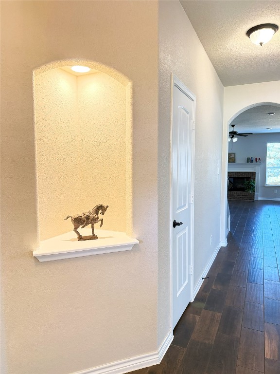 hall with a textured ceiling and dark wood-type flooring