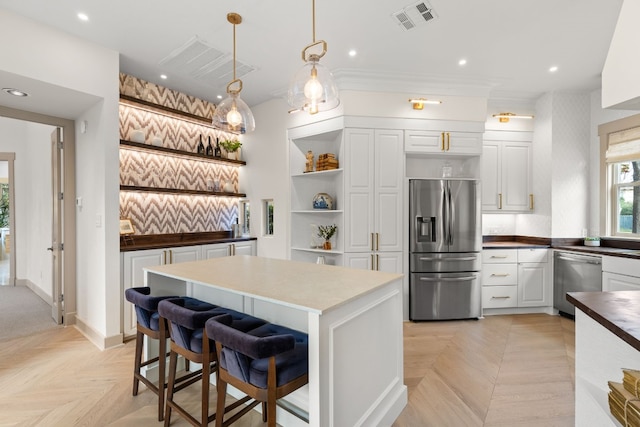 kitchen with light parquet floors, a breakfast bar area, decorative light fixtures, white cabinetry, and stainless steel appliances