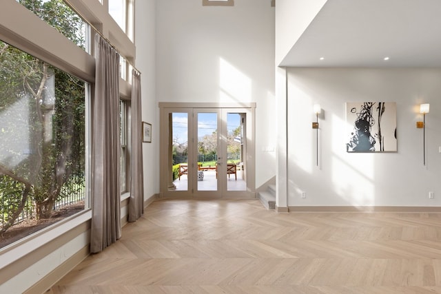 entryway with french doors, light parquet floors, and a high ceiling