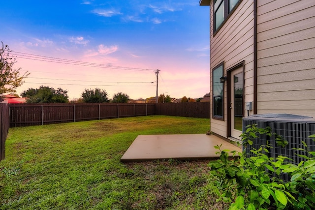 yard at dusk featuring central AC and a patio area