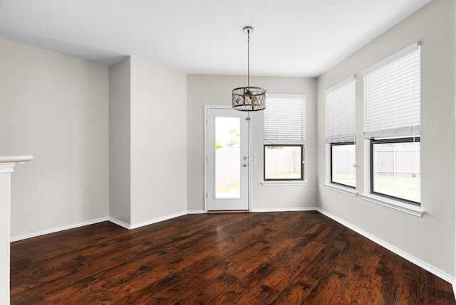 interior space with a healthy amount of sunlight, dark hardwood / wood-style flooring, and an inviting chandelier