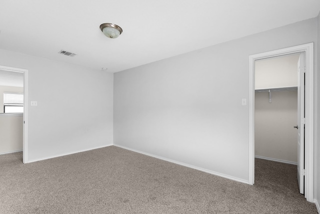 unfurnished bedroom featuring carpet flooring, a walk in closet, and a closet