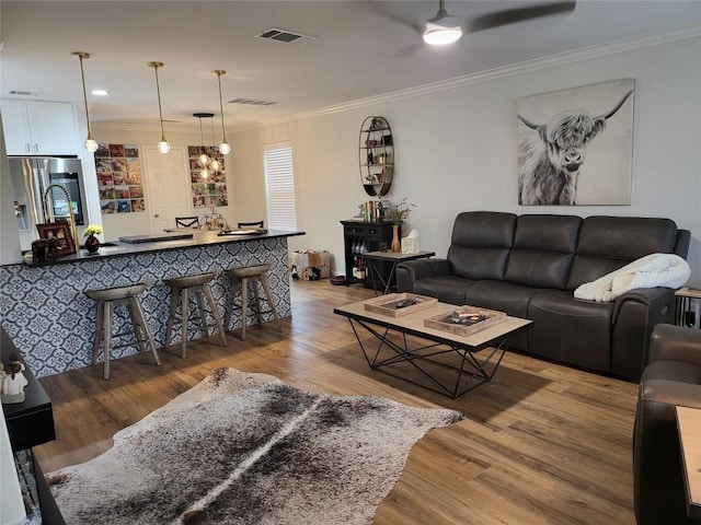 living room with crown molding, light hardwood / wood-style flooring, and ceiling fan