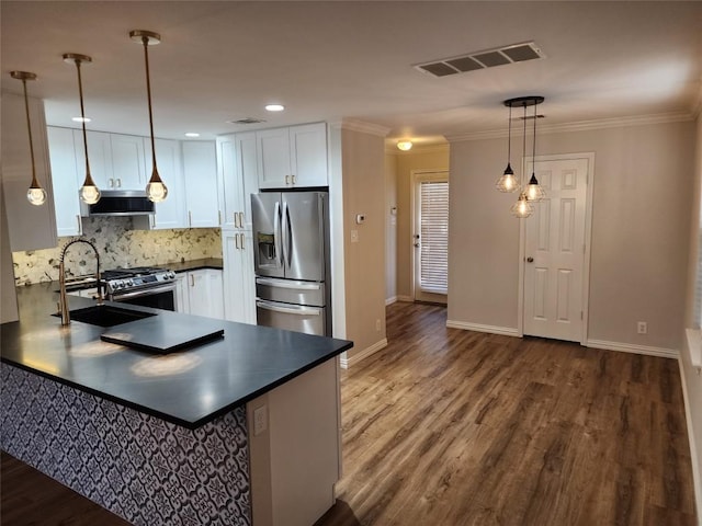 kitchen featuring pendant lighting, white cabinets, appliances with stainless steel finishes, wood-type flooring, and extractor fan