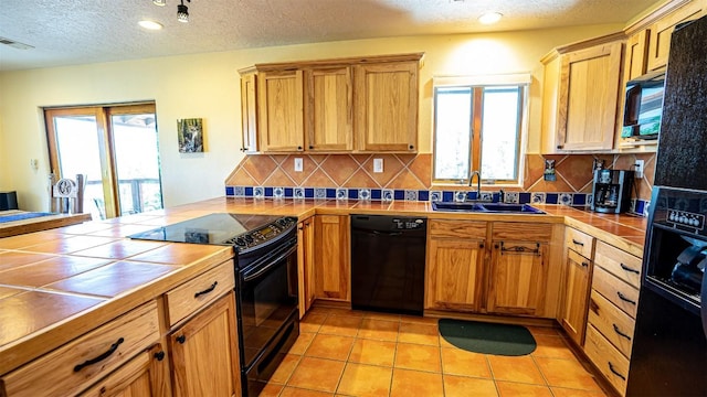 kitchen with tile countertops, black appliances, sink, decorative backsplash, and light tile patterned floors