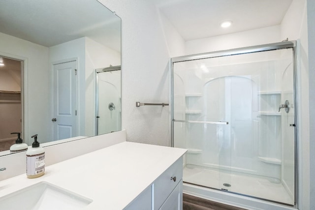 bathroom with hardwood / wood-style flooring, vanity, and a shower with door