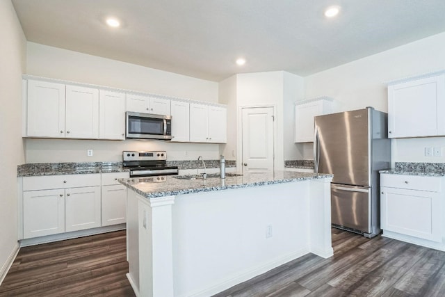 kitchen with white cabinets, appliances with stainless steel finishes, dark hardwood / wood-style floors, and an island with sink