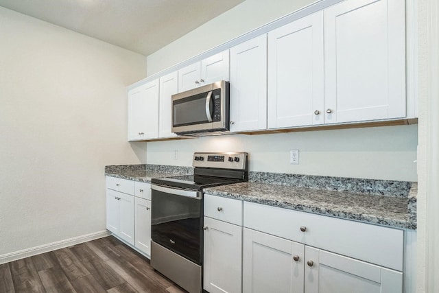 kitchen with dark hardwood / wood-style floors, white cabinetry, appliances with stainless steel finishes, and dark stone counters