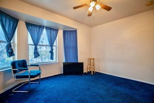 living area featuring ceiling fan and dark carpet