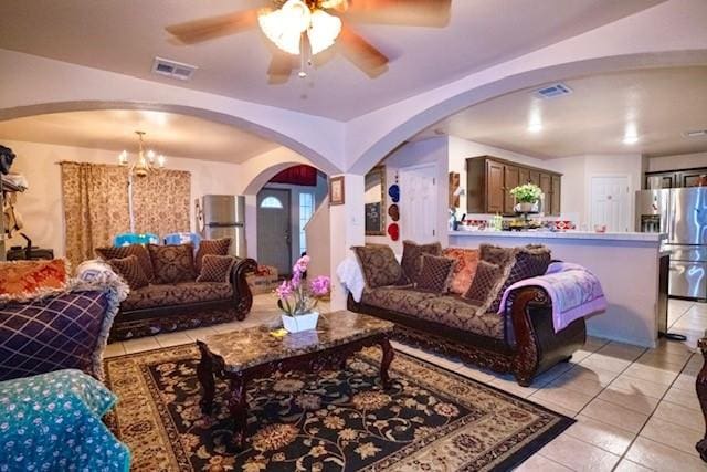 living room featuring light tile patterned flooring and ceiling fan with notable chandelier