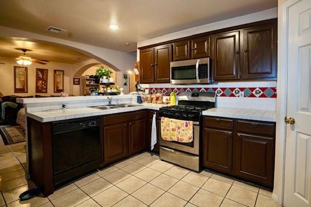 kitchen with kitchen peninsula, appliances with stainless steel finishes, backsplash, and tile countertops