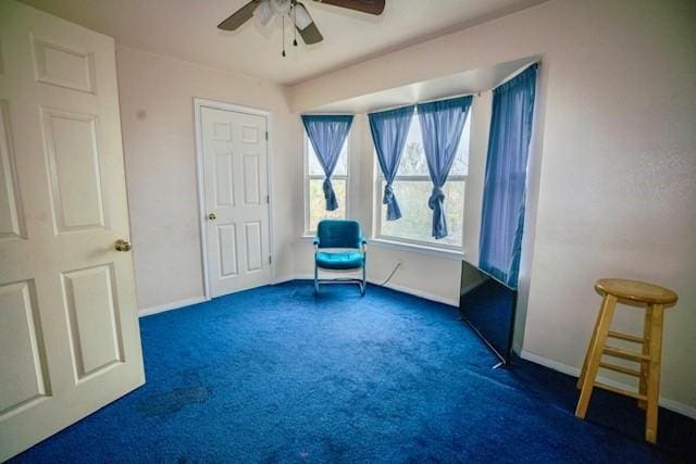 unfurnished room with ceiling fan and dark carpet