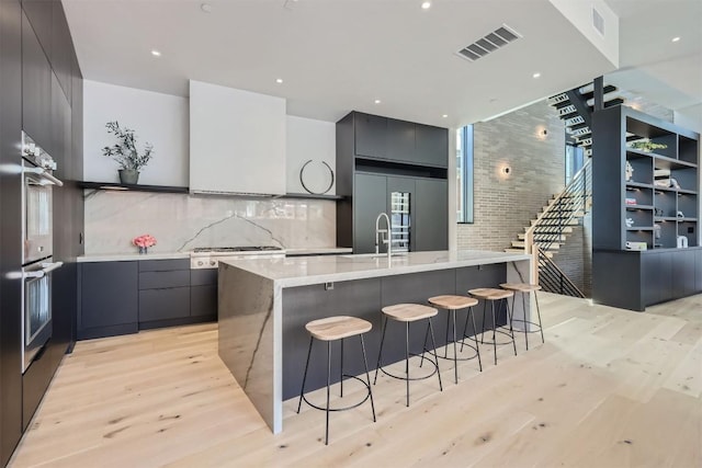 kitchen featuring light hardwood / wood-style floors, a kitchen breakfast bar, built in fridge, and a spacious island