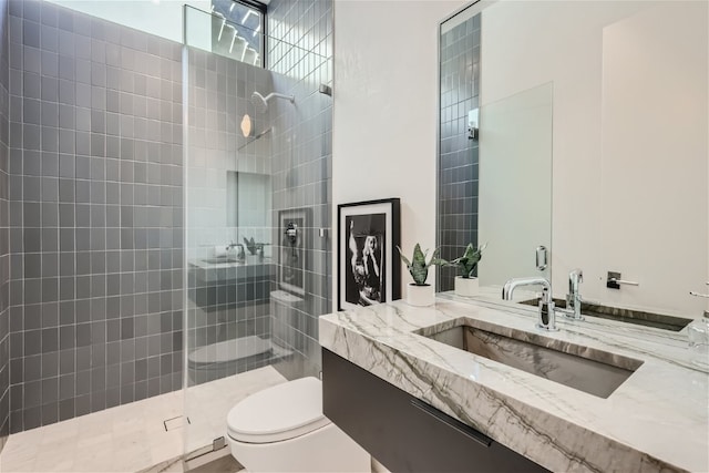 bathroom featuring vanity, tiled shower, and toilet