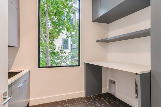 laundry room with cabinets, a wealth of natural light, and dark tile patterned flooring