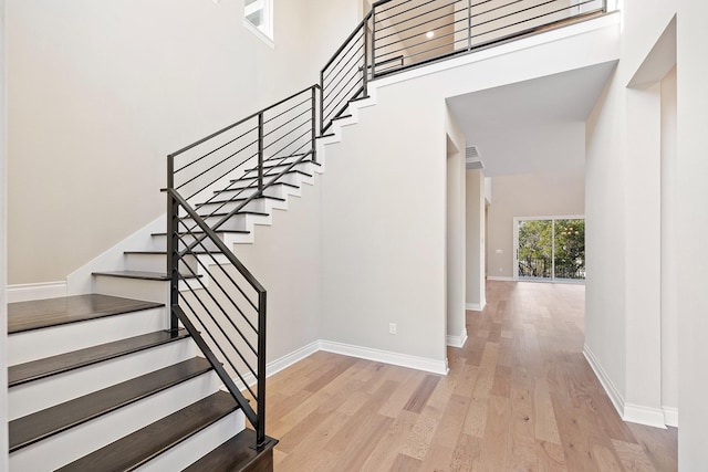 stairway featuring wood-type flooring and a high ceiling