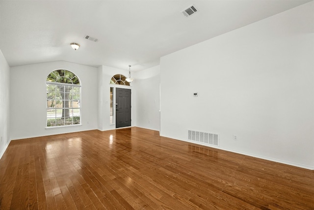 empty room with vaulted ceiling and hardwood / wood-style flooring