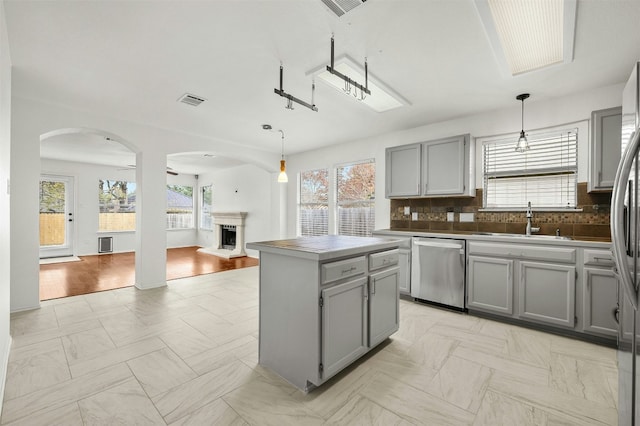 kitchen featuring sink, gray cabinetry, a center island, hanging light fixtures, and stainless steel dishwasher