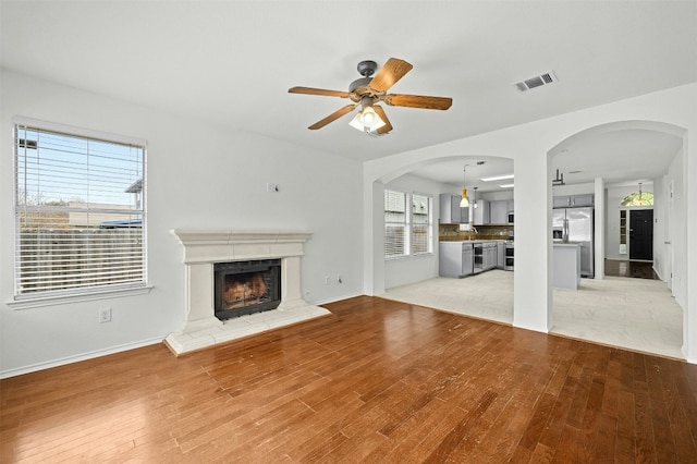 unfurnished living room with ceiling fan, sink, and light hardwood / wood-style floors