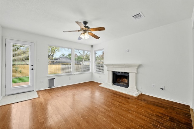 unfurnished living room with a healthy amount of sunlight, ceiling fan, and wood-type flooring