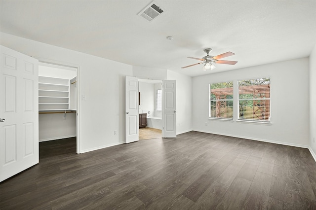 unfurnished bedroom with dark hardwood / wood-style flooring, a walk in closet, ceiling fan, connected bathroom, and a closet