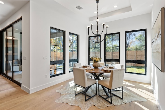 dining room with a wealth of natural light, an inviting chandelier, and light wood-type flooring