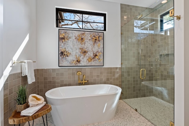 bathroom featuring a wealth of natural light, plus walk in shower, and tile walls