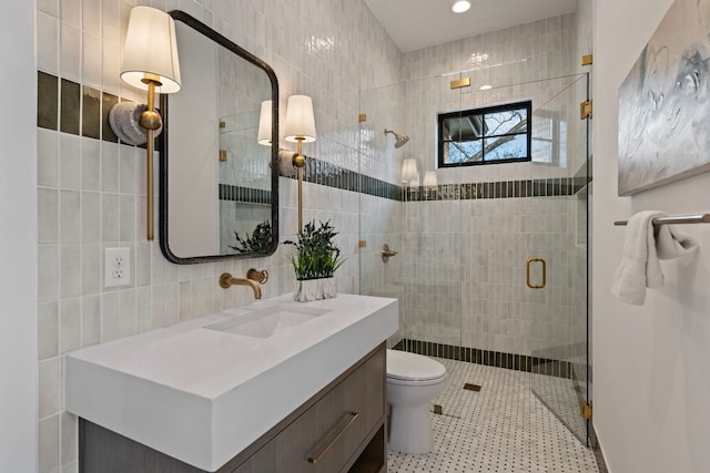 bathroom with a shower with door, vanity, and tile walls