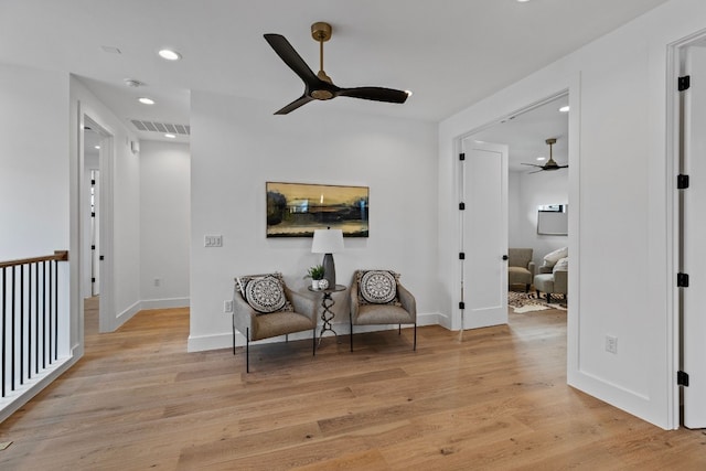 living area with ceiling fan and light hardwood / wood-style floors