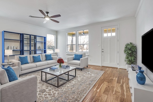 living room with light wood-style floors, crown molding, baseboards, and ceiling fan