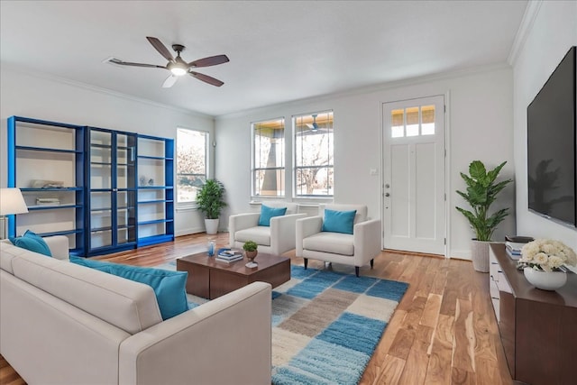 living area with baseboards, crown molding, a ceiling fan, and wood finished floors