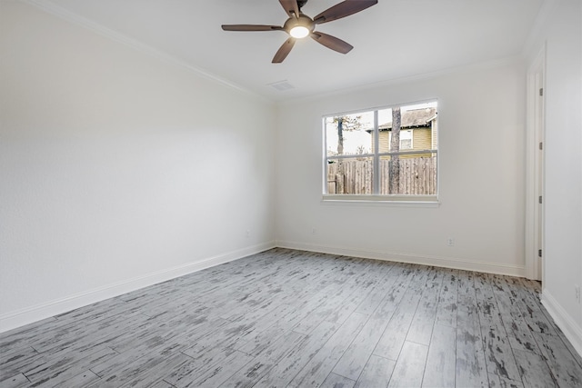 spare room featuring visible vents, ornamental molding, light wood-style floors, a ceiling fan, and baseboards